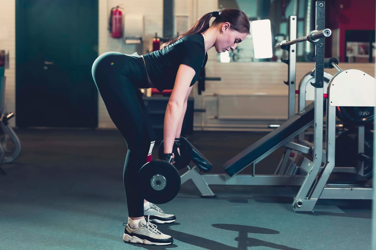 side-view-young-woman-lifting-weight-fitness-center