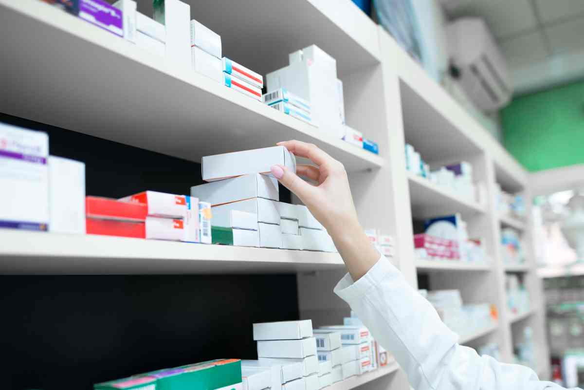 Closeup view of pharmacist hand taking medicine box from the shelf in drug store. PTCB top 200 drugs